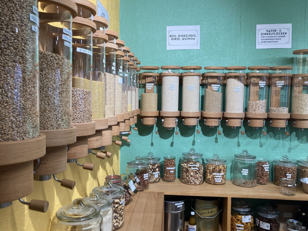 Das Bild zeigt eine Wand mit Lebensmittelspendern, die mit Getreide und Getreideflocken gefüllt sind.