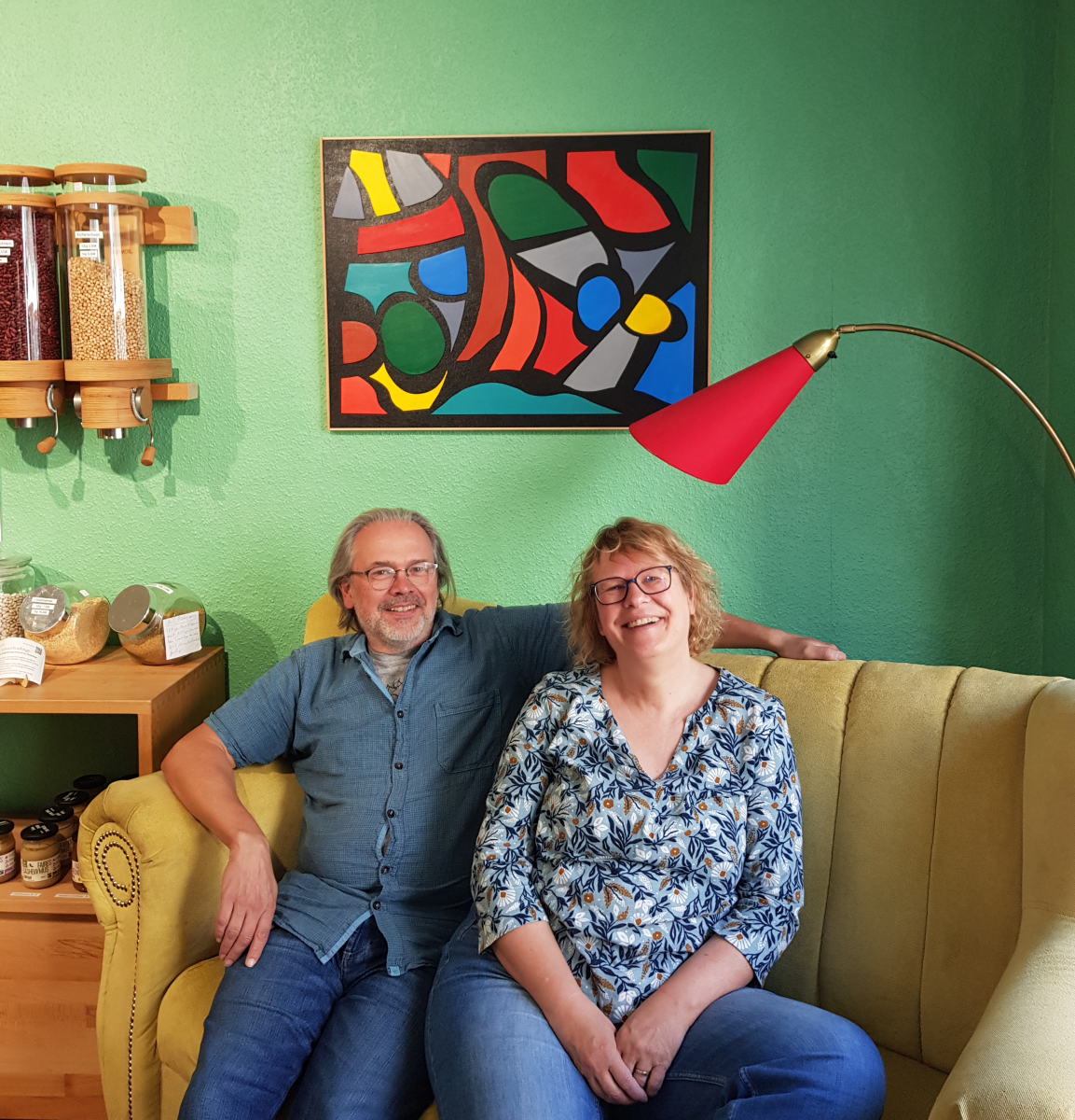 Das Bild zeigt Jörg und Anita Oelmann auf einem gelben Sofa im Unverpacktladen